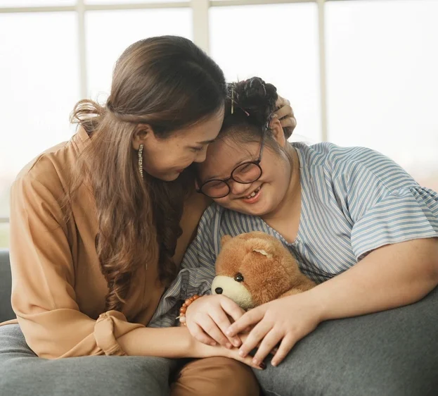 Support worker hugging disabled girl