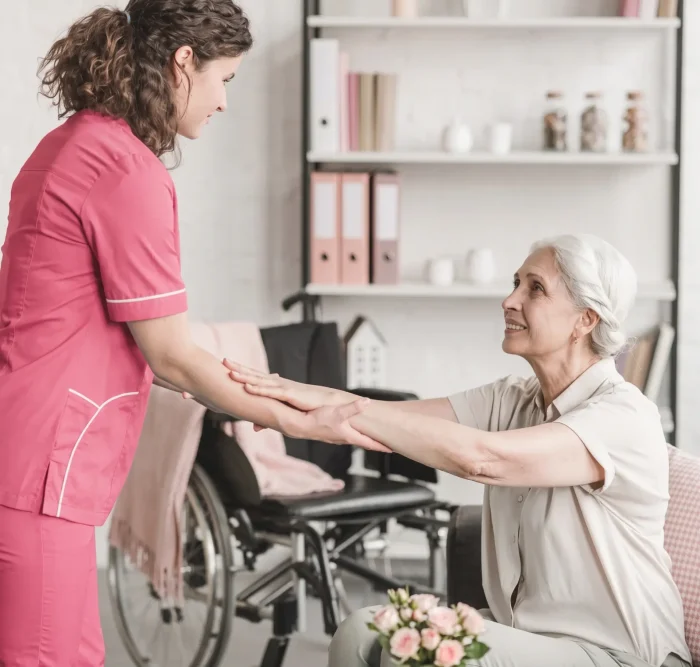 Nurse holding hands senior disabled woman sitting in wheelchair